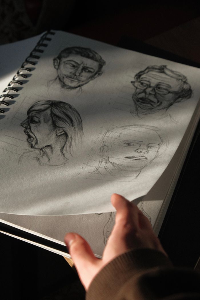 about-us-01 A notebook page with artistic pencil sketches captured in dramatic shadow and light.