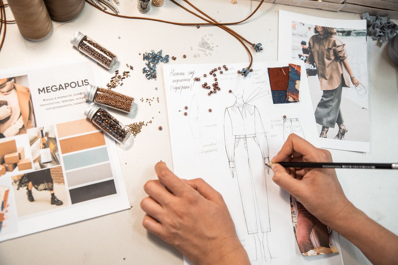 Mastering the First Impression: Your intriguing post title goes here Fashion designer sketching in a workspace with materials and mood boards.